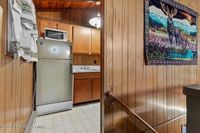 a view of a refrigerator in kitchen and an empty room