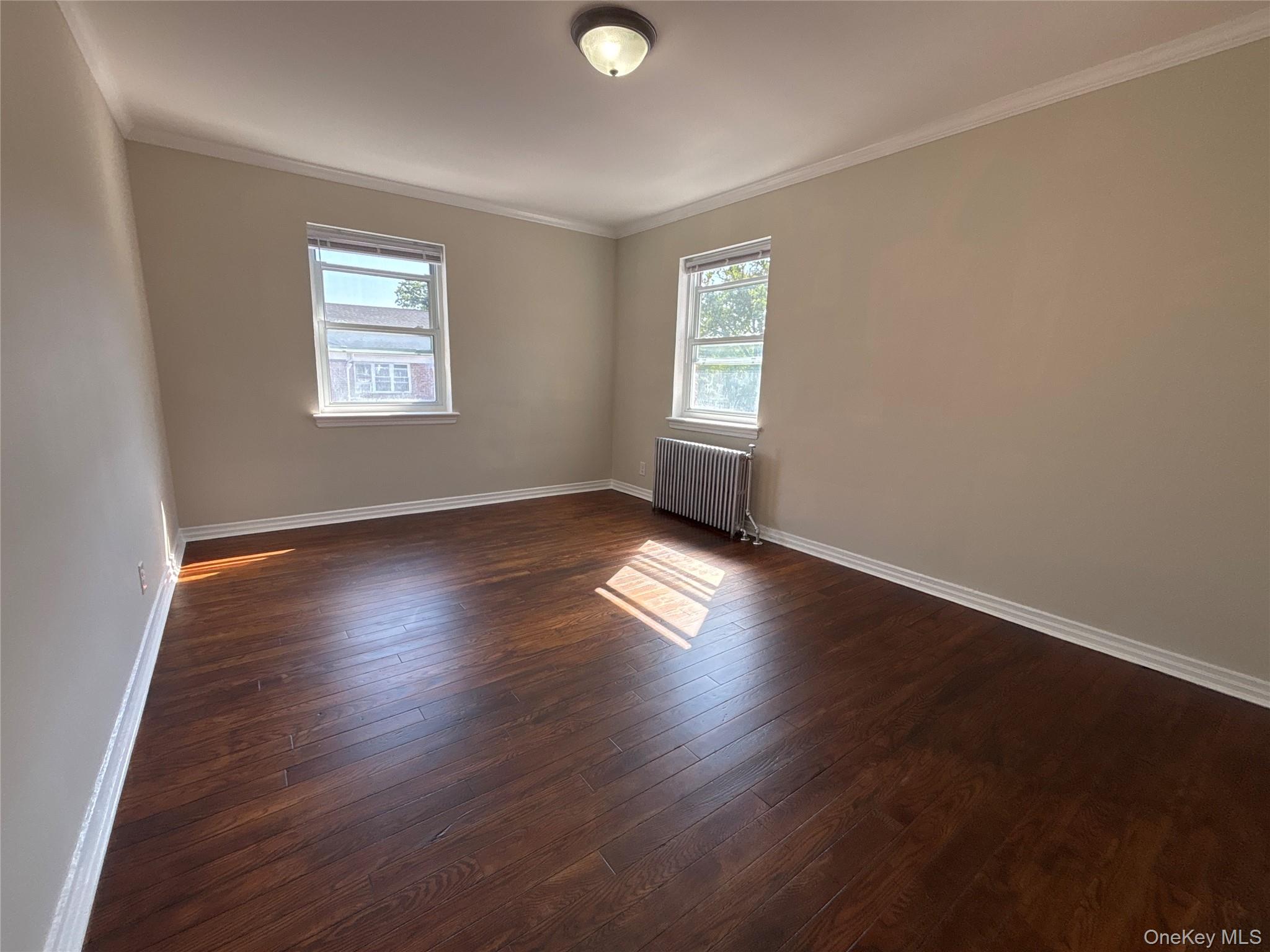37 Spruce Street, Unit 2 Great Neck, NY 11021 - Photo 5 of 18 an empty room with wooden floor and windows
