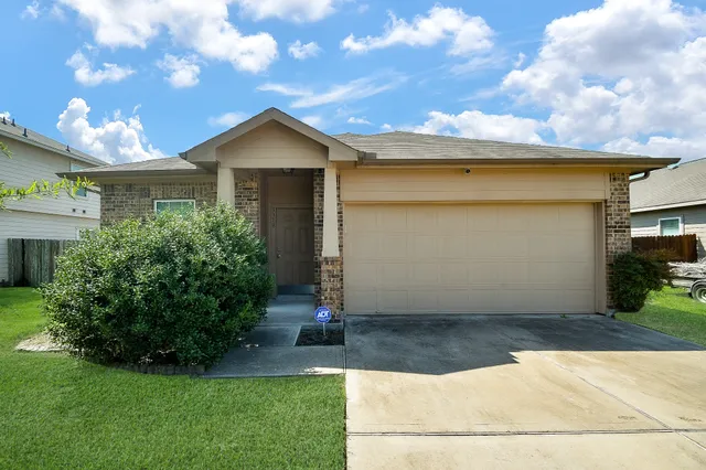a view of a house with a yard plants and large tree