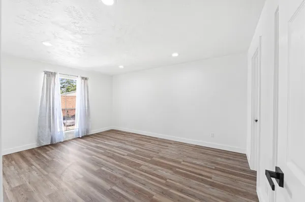 an empty room with wooden floor and windows