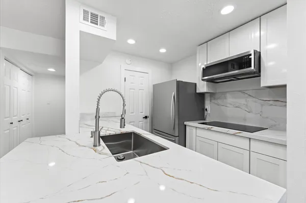 a kitchen with stainless steel appliances kitchen island granite countertop a sink and a stove top oven with wooden floor