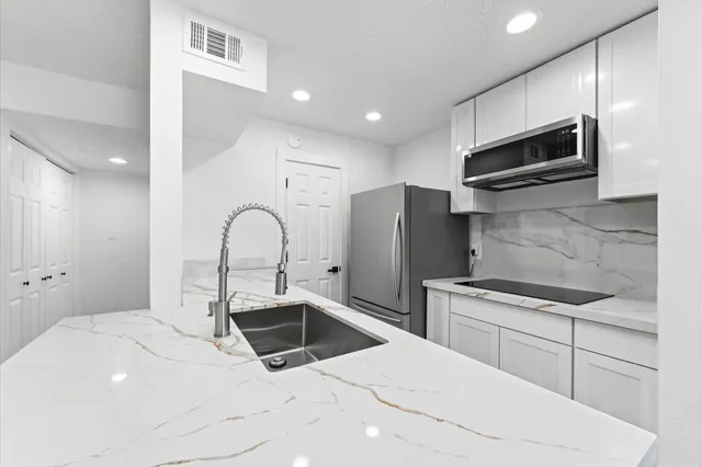 a kitchen with stainless steel appliances kitchen island granite countertop a sink and a stove top oven with wooden floor