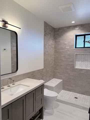a bathroom with a granite countertop sink toilet and shower