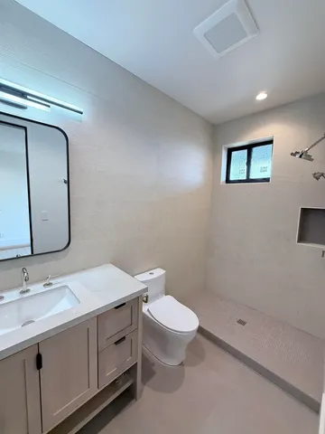 a bathroom with a toilet a sink a mirror and a shower