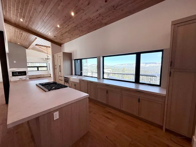 a kitchen with kitchen island a sink appliances wooden floor and a large window