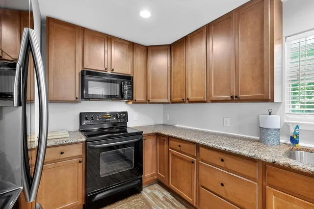 a kitchen with granite countertop stainless steel appliances a stove microwave and refrigerator