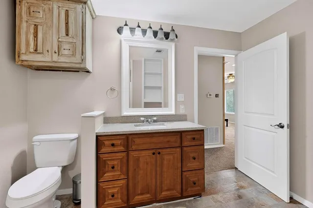a bathroom with a granite countertop toilet sink and mirror