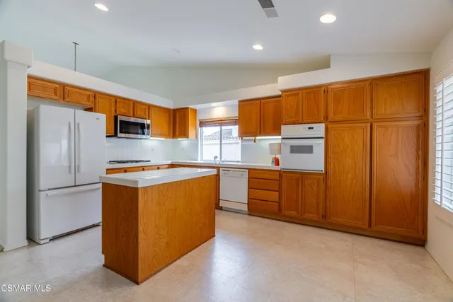 a kitchen with stainless steel appliances granite countertop a refrigerator a sink dishwasher and a stove