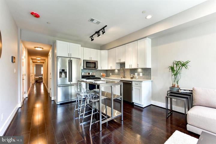 1453 Girard Street Northwest, Unit 3 Washington, DC 20009 - Photo 4 of 21 a kitchen with a table chairs refrigerator and microwave