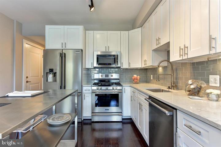 1453 Girard Street Northwest, Unit 3 Washington, DC 20009 - Photo 6 of 21 a kitchen with stainless steel appliances a stove a sink dishwasher a refrigerator and cabinets with wooden floor
