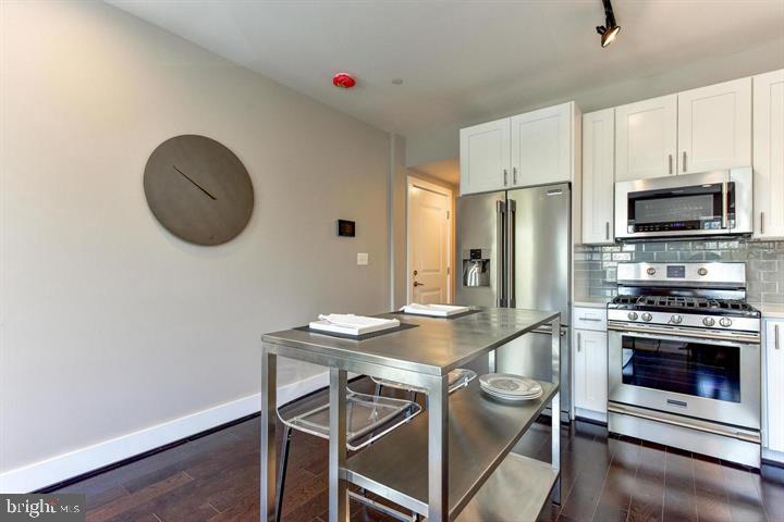 1453 Girard Street Northwest, Unit 3 Washington, DC 20009 - Photo 7 of 21 a kitchen with stainless steel appliances granite countertop a stove a refrigerator and a dining table with wooden floor