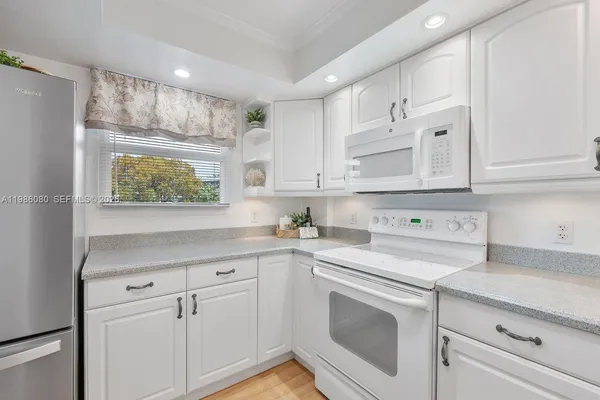 a kitchen with white cabinets and white appliances