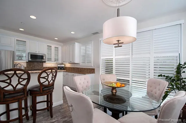 a kitchen with stainless steel appliances a dining table chairs and a refrigerator