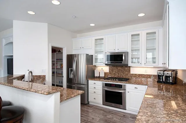 a kitchen with stainless steel appliances granite countertop a stove a sink and a refrigerator