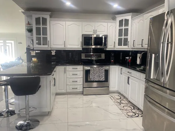a kitchen with stainless steel appliances granite countertop a refrigerator and a stove top oven
