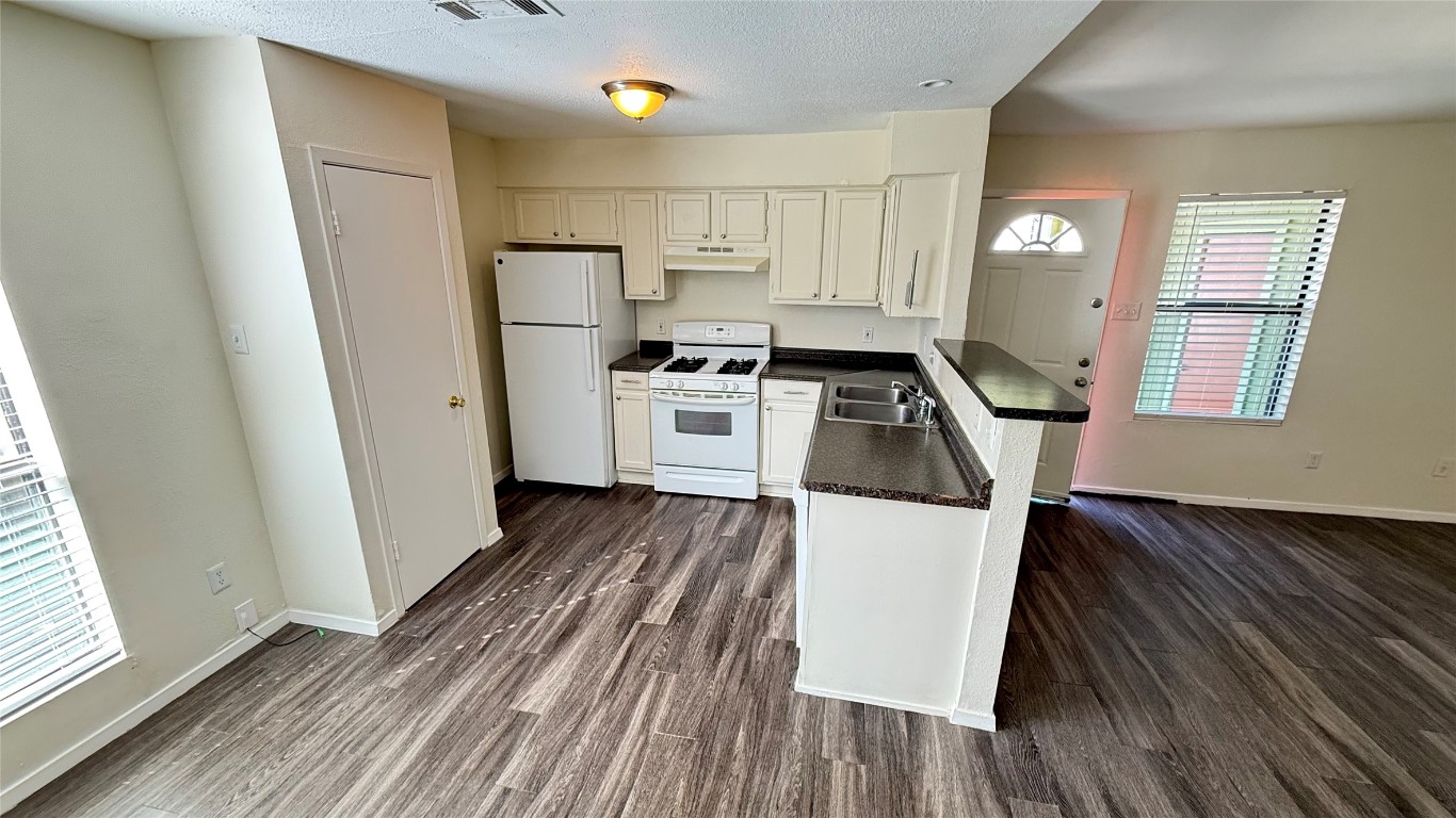 2213 Yellow Jacket Lane, Unit B Austin, TX 78741 - Photo 2 of 6 a kitchen with a refrigerator a stove top oven and wooden floor