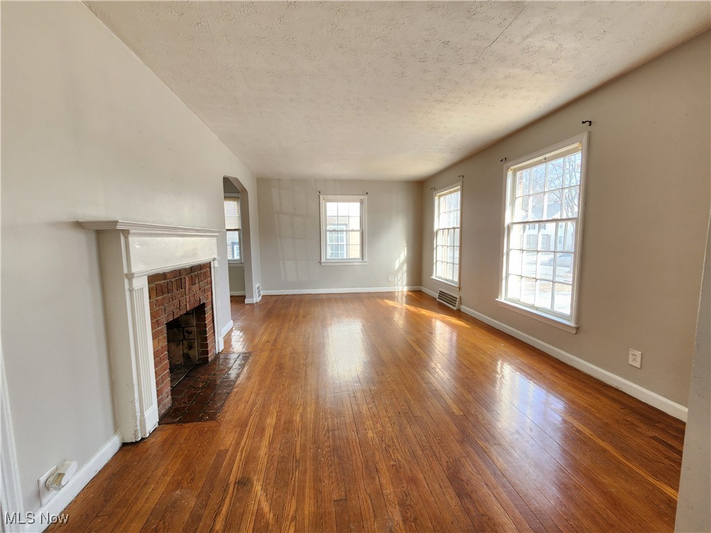 1160 Brentwood Road Cleveland, OH 44121 - Photo 6 of 26 Unfurnished living room featuring hardwood flooring, a fireplace, and a textured ceiling