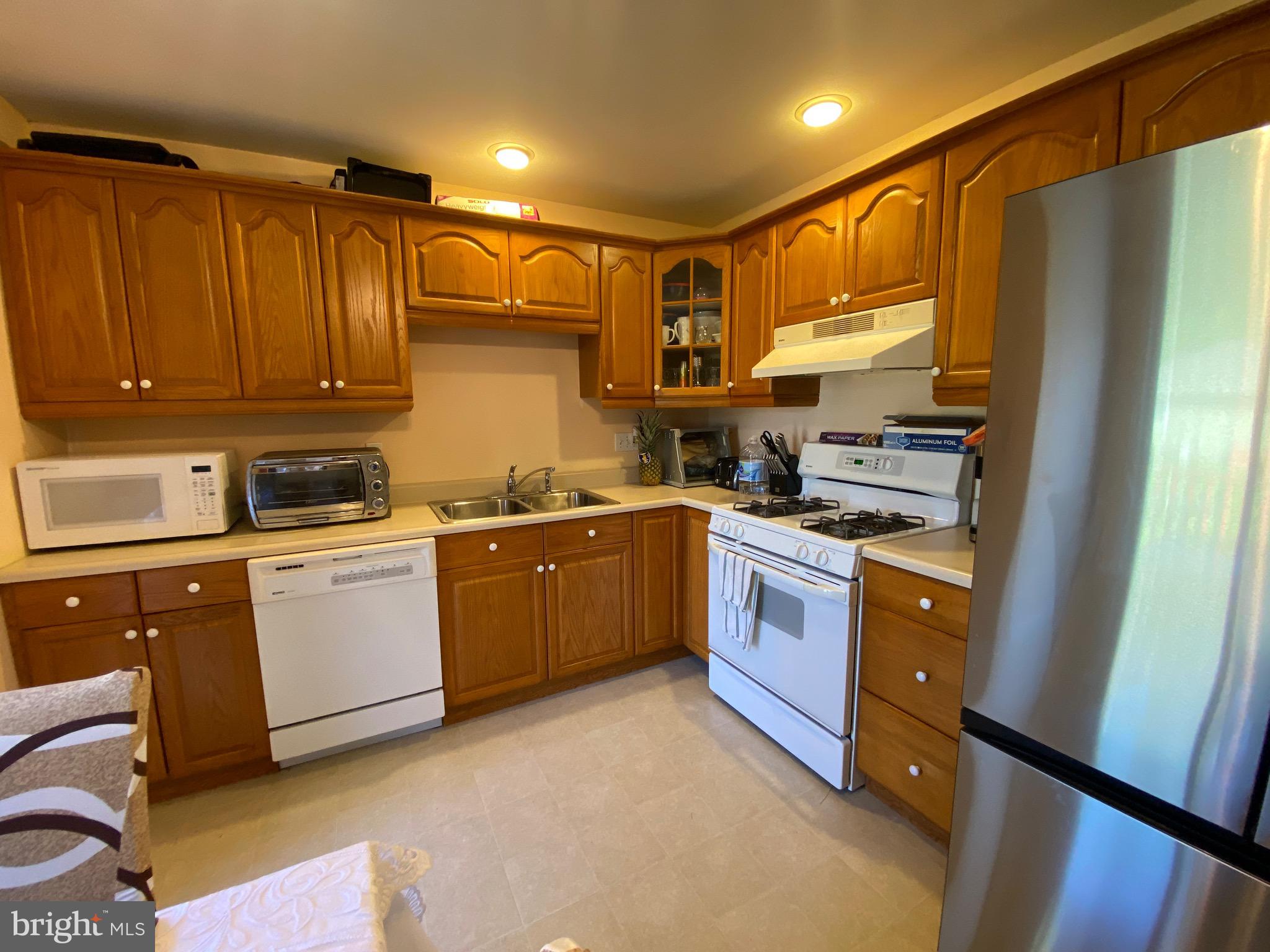 42 Harvard Road Pennsville, NJ 08070 - Photo 13 of 26 a kitchen with stainless steel appliances granite countertop a refrigerator a sink dishwasher a stove and white cabinets with wooden floor