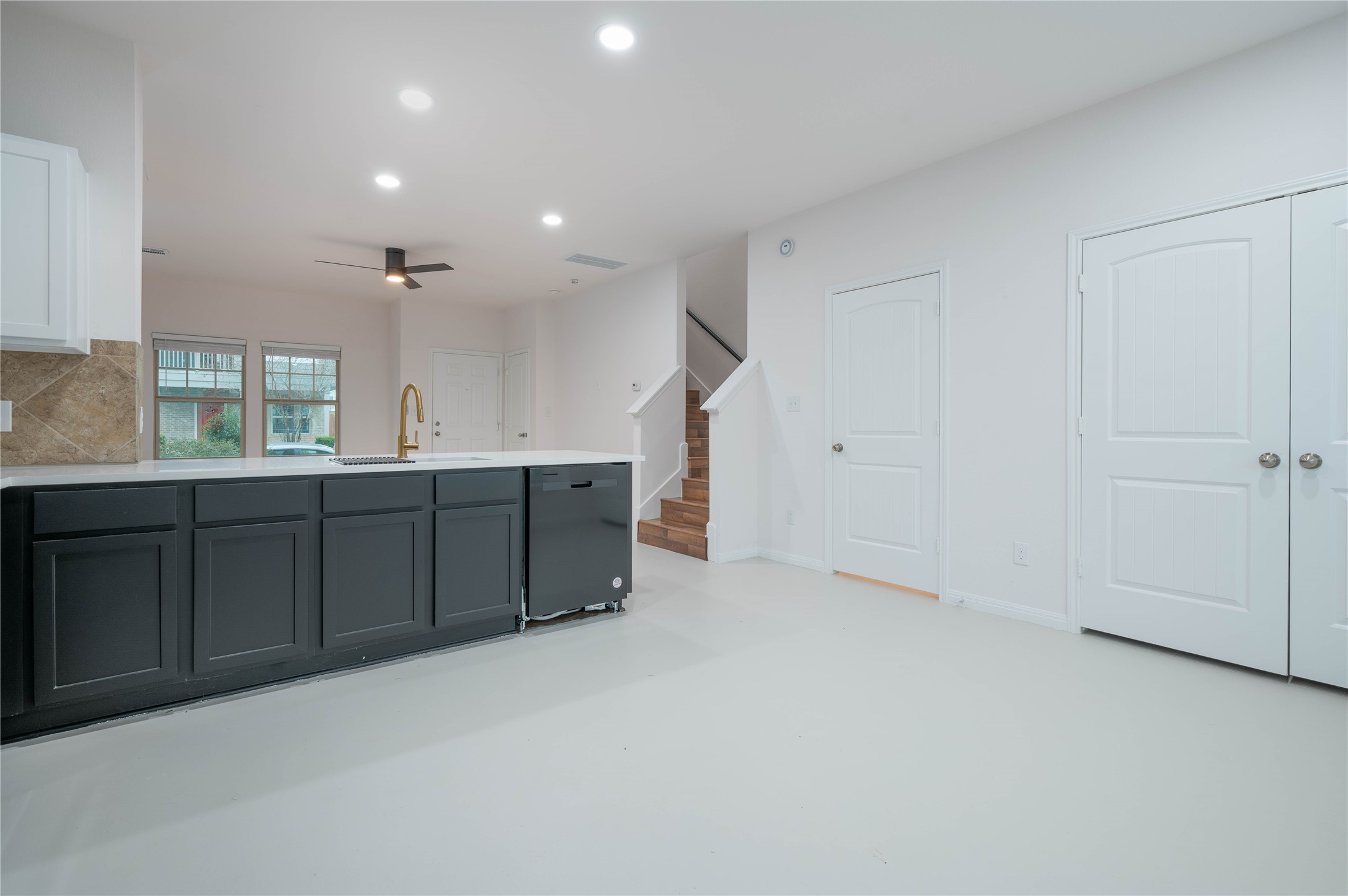 Kitchen with sink, dishwasher, ceiling fan, decorative backsplash, and white cabinets