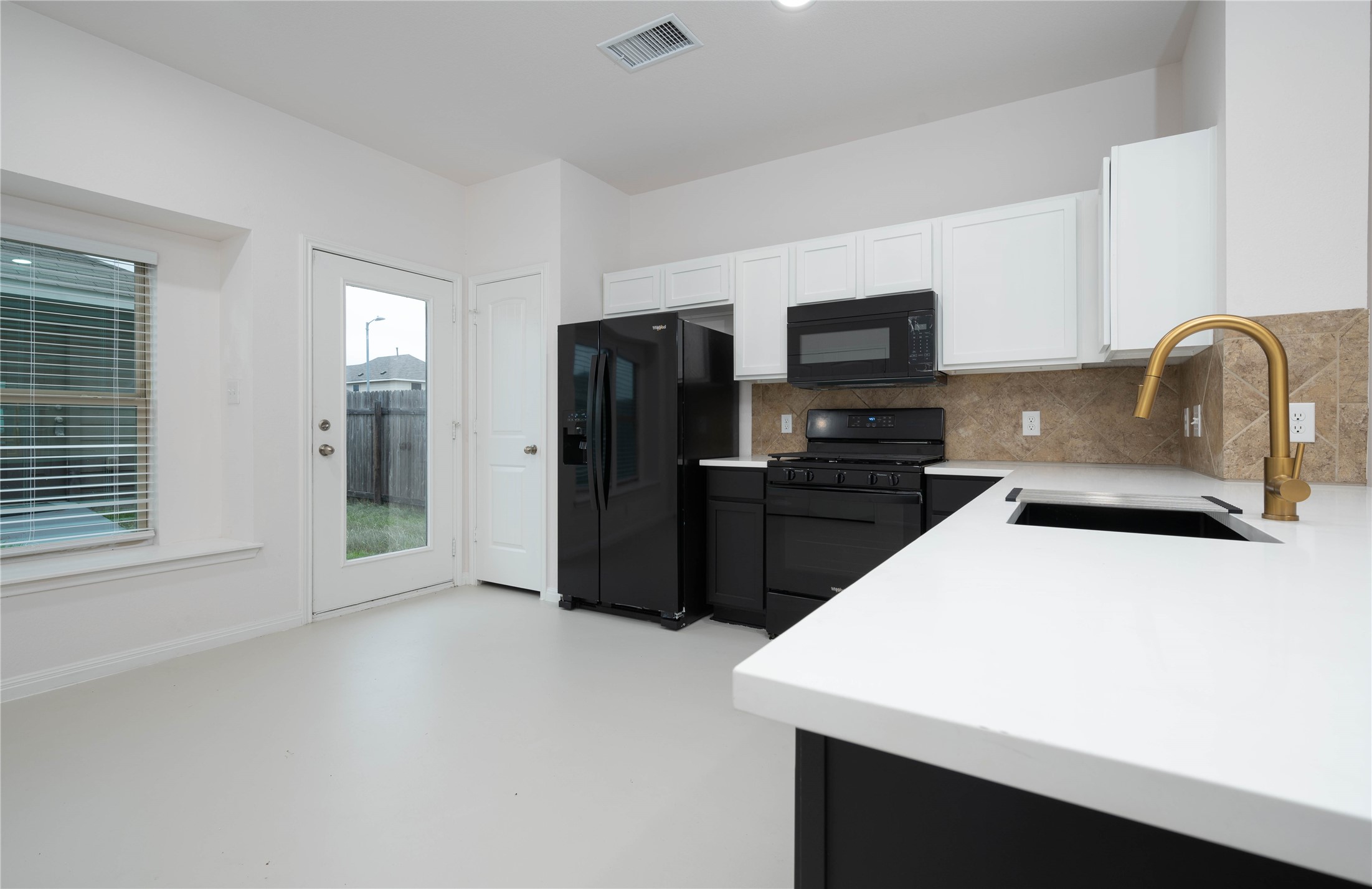 4514 Truth Way Austin, TX 78725 - Photo 5 of 20 Kitchen with white cabinetry, sink, decorative backsplash, and black appliances