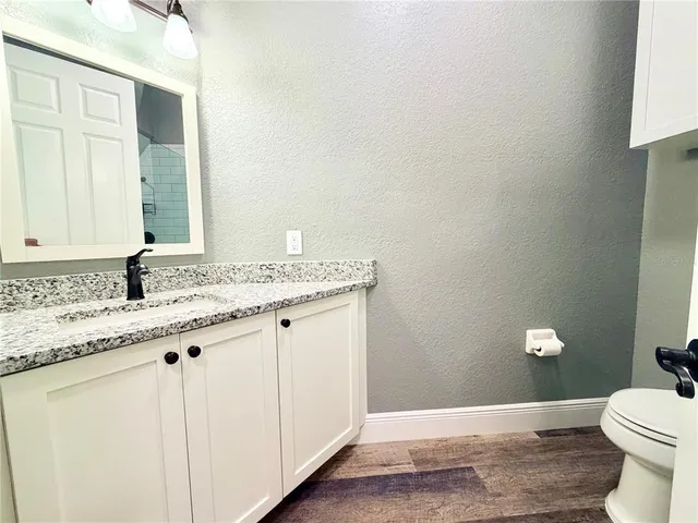 a bathroom with a granite countertop sink a toilet and a mirror