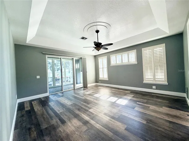 a view of an empty room with a window and wooden floor