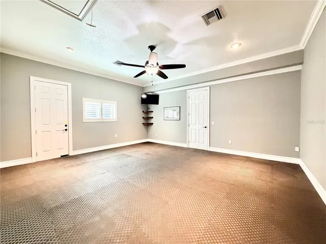 an empty room with ceiling fan and windows