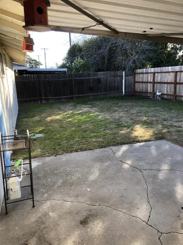 a view of a backyard with chairs and potted plants