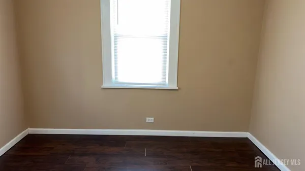 an empty room with wooden floor and window