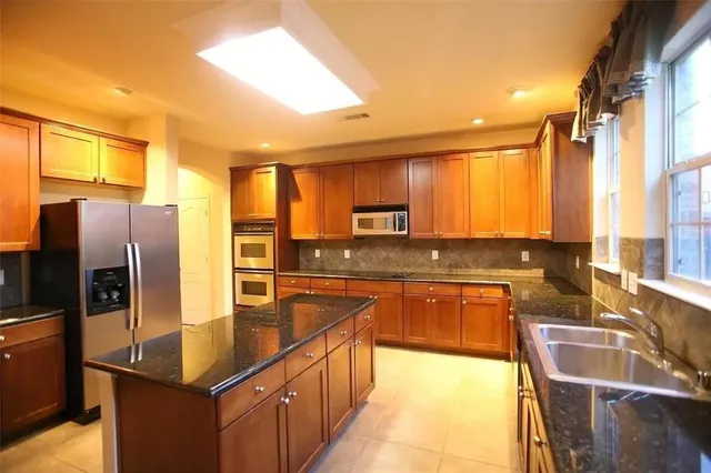 a kitchen with stainless steel appliances granite countertop a sink a stove and refrigerator