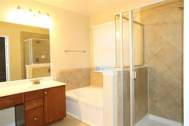 a bathroom with a tub sink vanity and mirror