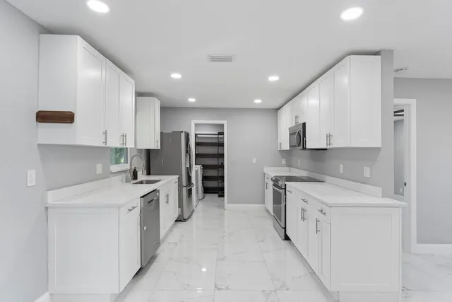 a kitchen with stainless steel appliances kitchen island granite countertop a sink and cabinets