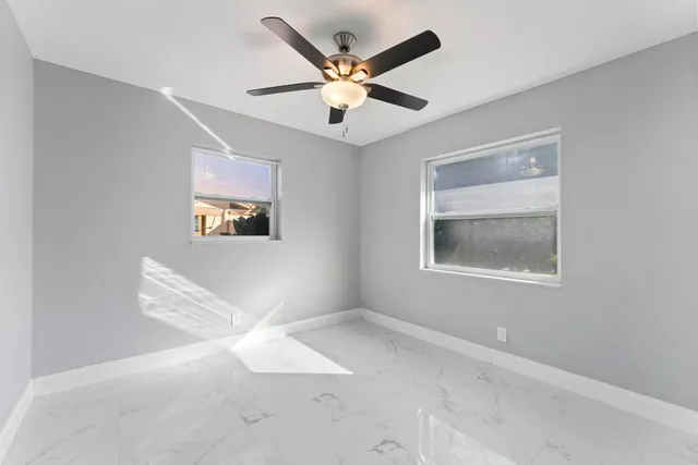 a view of an empty room with window and ceiling fan