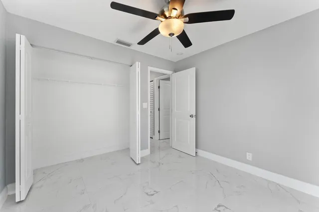 an empty room with closet and a ceiling fan