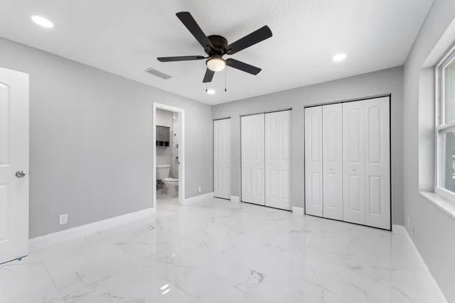 an empty room with ceiling fan and windows