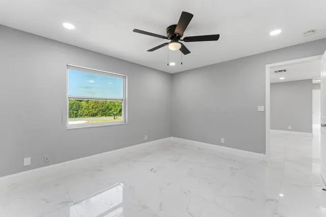 an empty room with a ceiling fan and a window