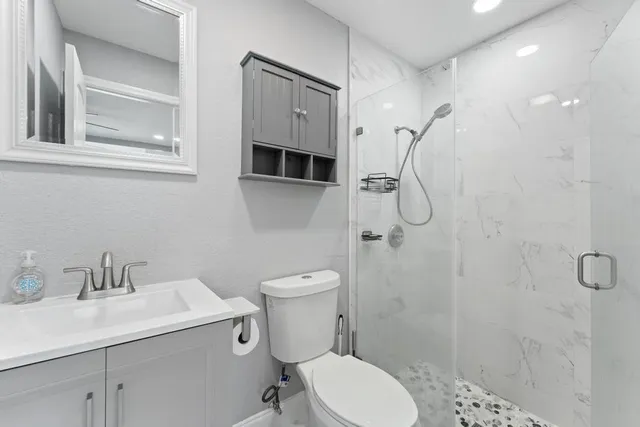 a bathroom with a granite countertop sink toilet and shower
