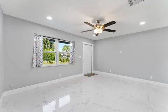 an empty room with window and ceiling fan