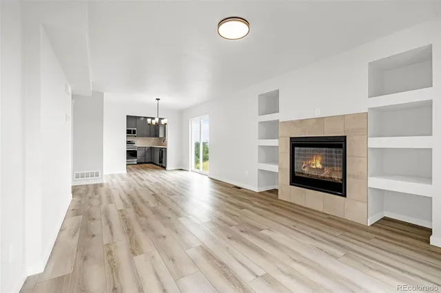 an empty room with a fireplace and wooden floor