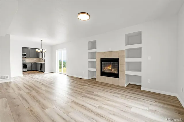 a view of empty room with a fireplace and wooden floor