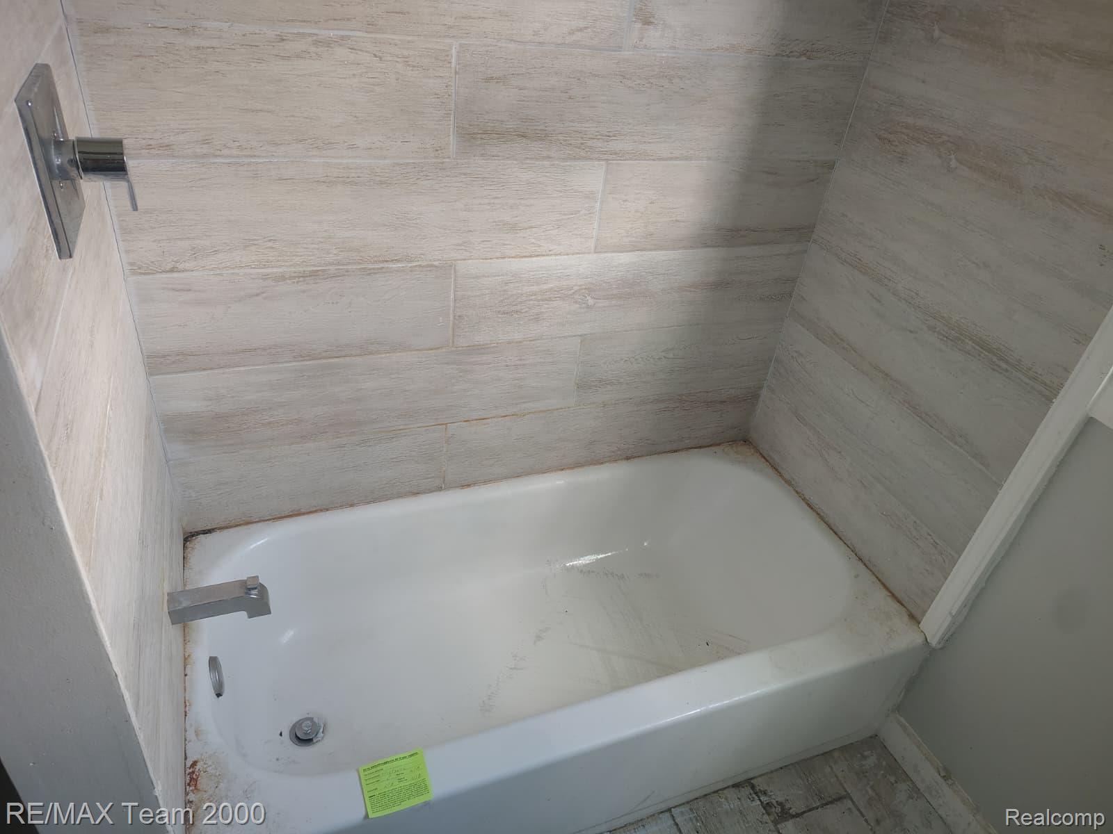 8860 Appoline Street Detroit, MI 48228 - Photo 16 of 45 White bathtub enclosure featuring light-toned rectangular tile surround