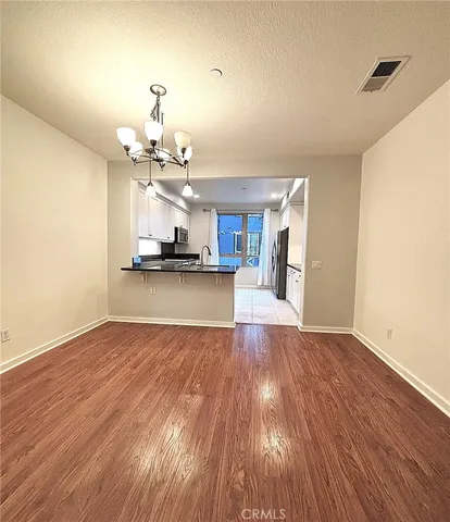 a view of a room with wooden floor and kitchen view
