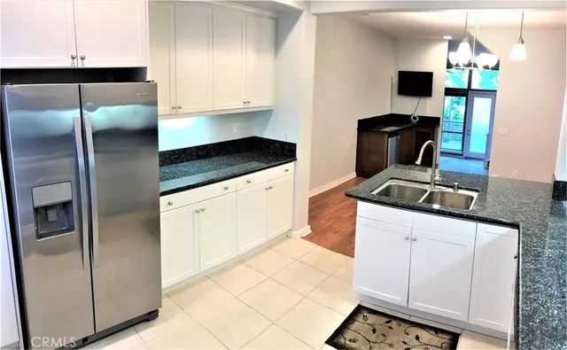 a kitchen with stainless steel appliances granite countertop a refrigerator a stove and a sink with wooden floor