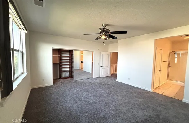 an empty room with closet and a chandelier fan