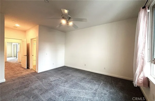 an empty room with chandelier fan and windows