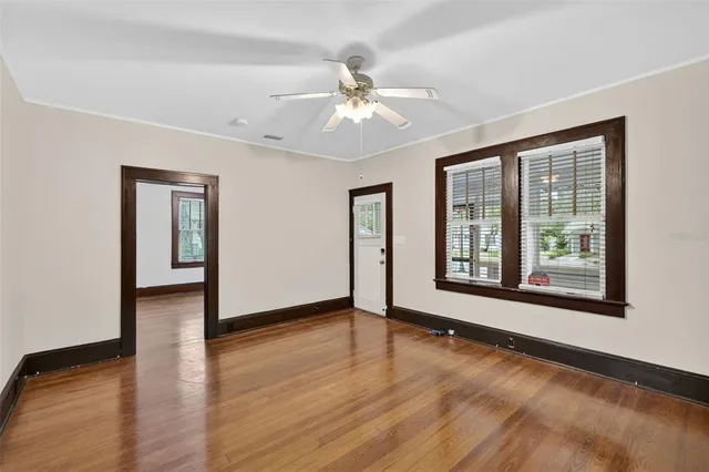 a view of an empty room with wooden floor and a window