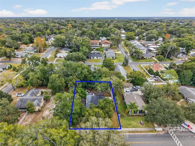 an aerial view of a residential houses with outdoor space and trees