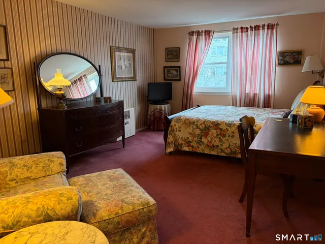 a bedroom with a bed and a dresser next to a window