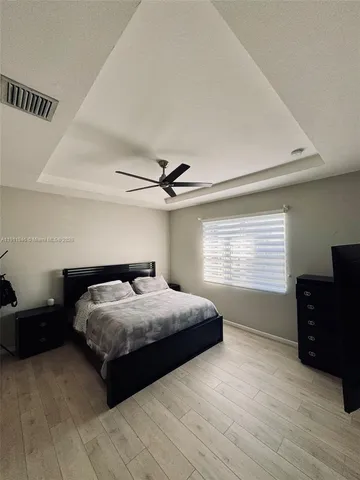a bedroom with a bed and dresser with wooden floor