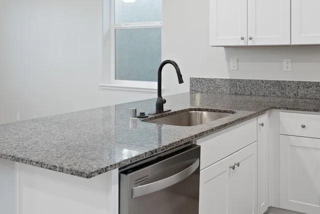 a kitchen with granite countertop a sink and cabinets